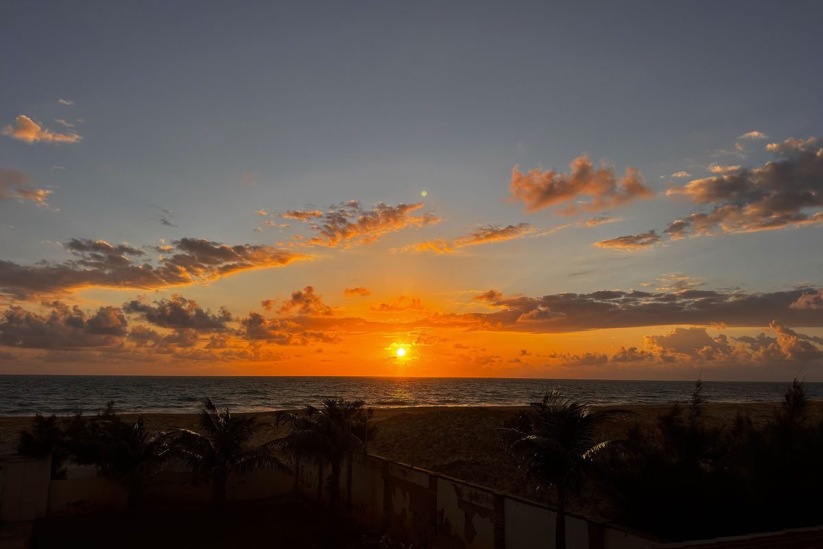 Céu avermelhado com o sol no horizonte, ao amanhecer.